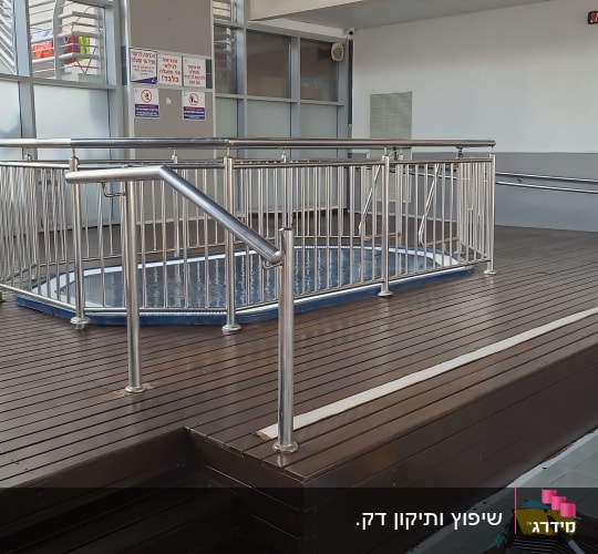 רצפת עץ עם מעקה מתכת סביב בריכה קטנה